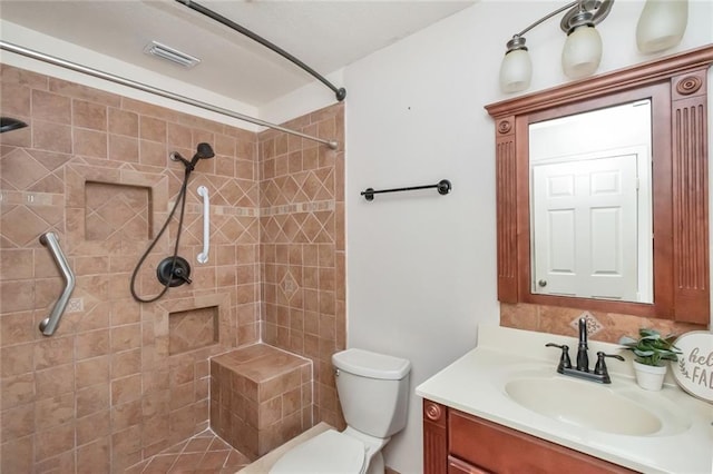 bathroom featuring vanity, toilet, and a tile shower