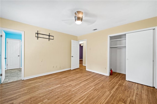 unfurnished bedroom with ceiling fan, light wood-type flooring, and a closet