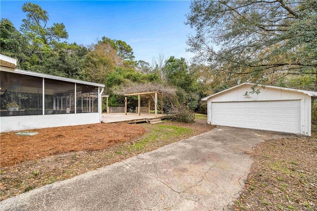 view of yard featuring an outbuilding, a garage, a pergola, and a sunroom