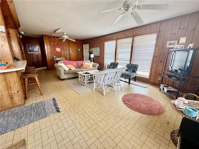 living room featuring wood walls, brick patterned floor, and ceiling fan