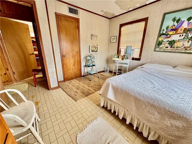 bedroom featuring brick floor, visible vents, baseboards, and crown molding