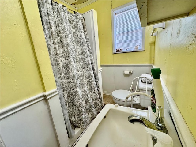 bathroom featuring tile patterned floors, a wainscoted wall, curtained shower, and toilet