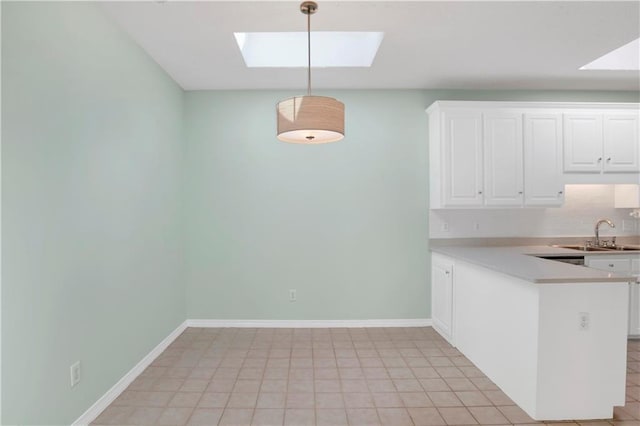 kitchen featuring a skylight, sink, kitchen peninsula, pendant lighting, and white cabinets