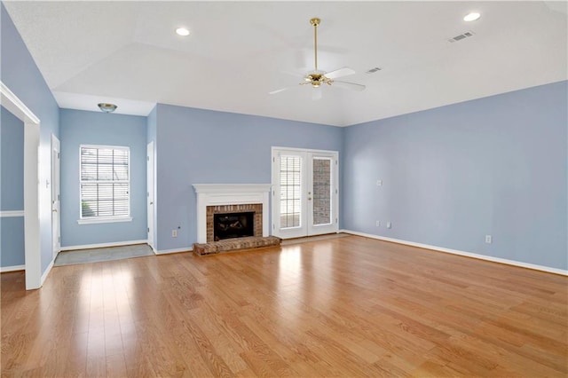 unfurnished living room with light hardwood / wood-style floors, a brick fireplace, vaulted ceiling, and ceiling fan