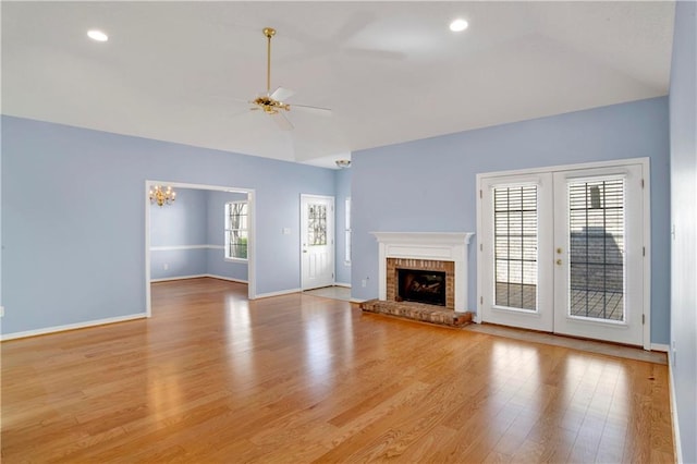 unfurnished living room featuring french doors, a fireplace, light hardwood / wood-style floors, and ceiling fan