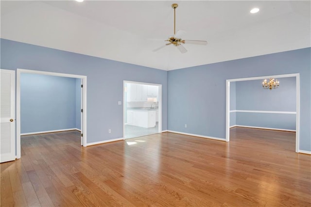 unfurnished room with sink, wood-type flooring, and ceiling fan with notable chandelier