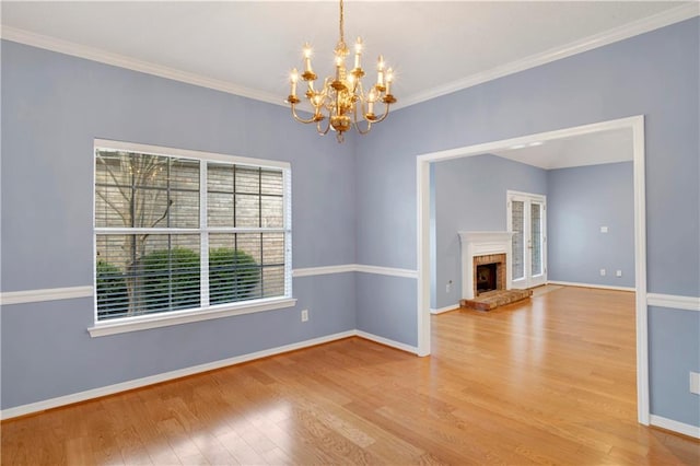 interior space featuring crown molding, wood-type flooring, an inviting chandelier, and a brick fireplace