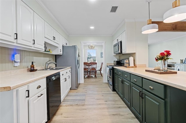 kitchen with appliances with stainless steel finishes, decorative light fixtures, white cabinetry, crown molding, and light hardwood / wood-style flooring