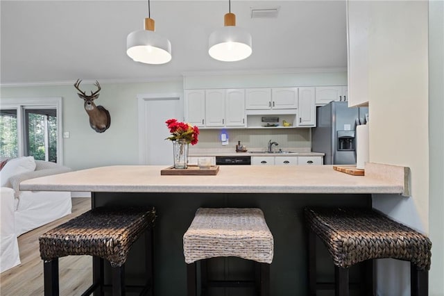 kitchen featuring pendant lighting, white cabinetry, sink, a kitchen bar, and stainless steel fridge with ice dispenser