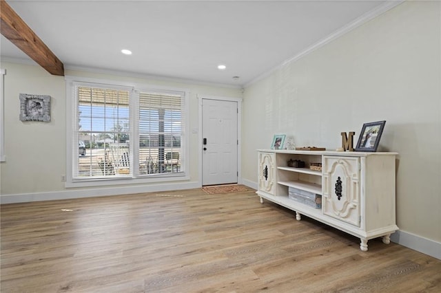 foyer entrance featuring beam ceiling, crown molding, and light wood-type flooring