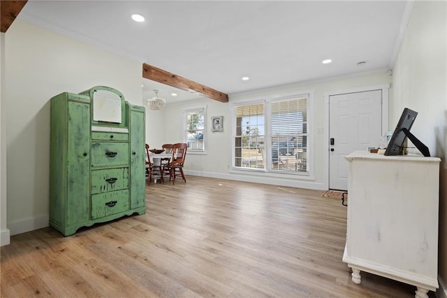 interior space featuring an inviting chandelier, light hardwood / wood-style flooring, ornamental molding, and beamed ceiling