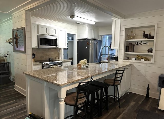 2911 Thornhill Dr, Mobile, AL 36606 - kitchen featuring stainless steel appliances, dark wood-style floors, white cabinets, a peninsula, and a breakfast bar