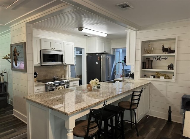2911 Thornhill Dr, Mobile, AL 36606 - kitchen featuring stainless steel appliances, dark wood-style flooring, a peninsula, a breakfast bar, and light stone counters