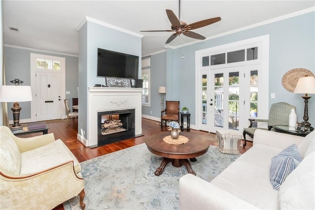 living room with a wealth of natural light, crown molding, and dark wood-type flooring