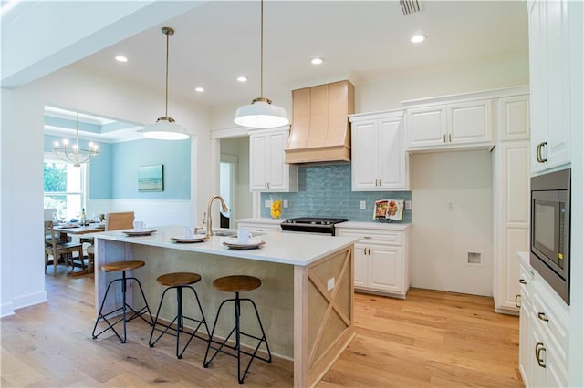 305 Hannah Chase Way, Satsuma, AL 36572 - kitchen with custom range hood, built in microwave, light wood-style floors, a kitchen breakfast bar, and a wainscoted wall