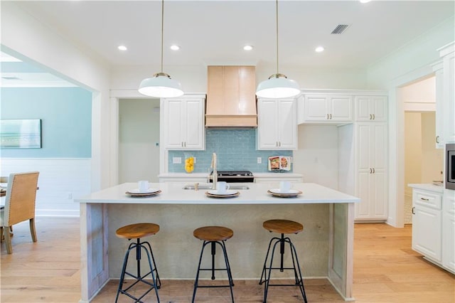 305 Hannah Chase Way, Satsuma, AL 36572 - kitchen with premium range hood, light wood-type flooring, light countertops, a breakfast bar area, and pendant lighting