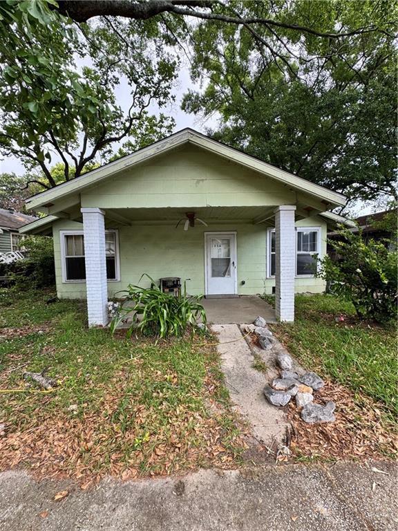 bungalow featuring concrete block siding, covered porch, and ceiling fan
