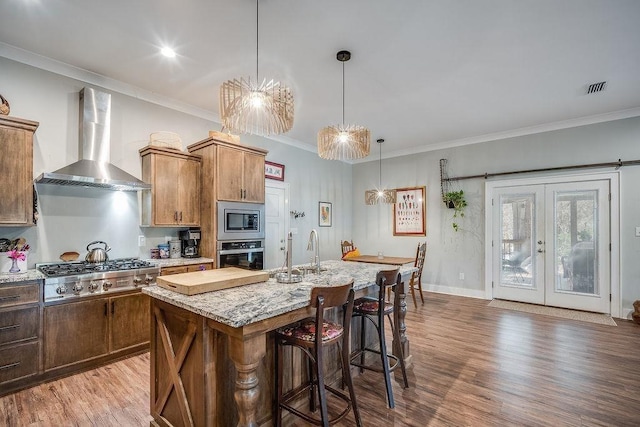7420 Pake Rd, Saraland, AL 36571 - kitchen featuring wood finished floors, appliances with stainless steel finishes, wall chimney range hood, visible vents, and ornamental molding