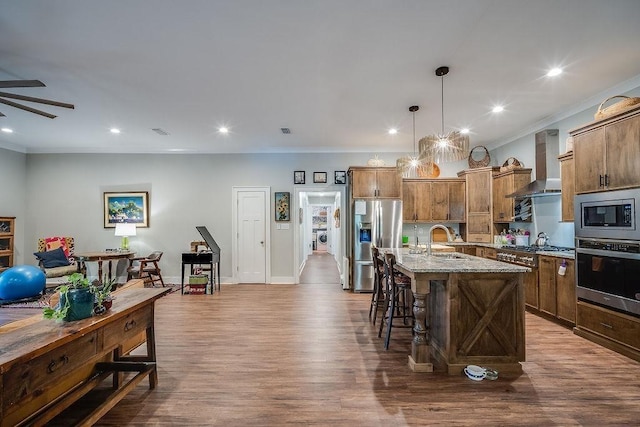 7420 Pake Rd, Saraland, AL 36571 - kitchen with dark wood-style flooring, stainless steel appliances, a sink, a breakfast bar area, and wall chimney range hood