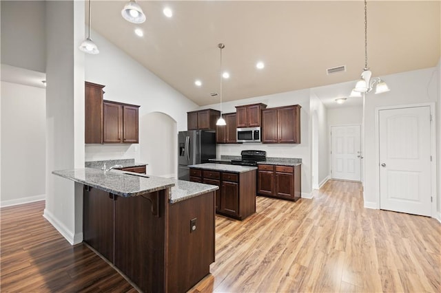 kitchen featuring light hardwood / wood-style floors, pendant lighting, light stone countertops, and stainless steel appliances