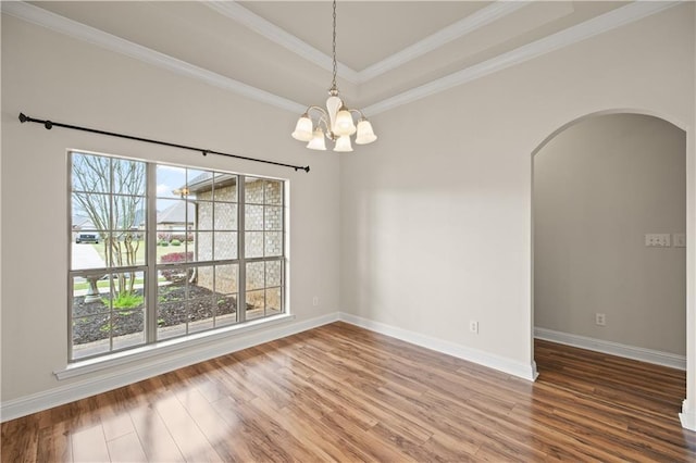 unfurnished room with ornamental molding, a raised ceiling, hardwood / wood-style floors, and a notable chandelier