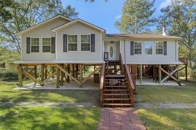 raised beach house with a front lawn and a patio area