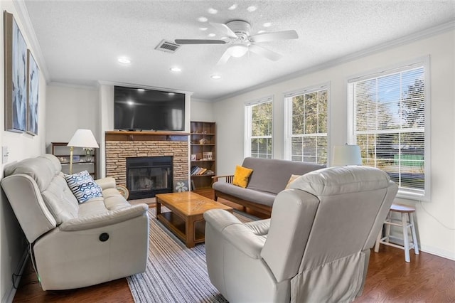 living room with a fireplace, a textured ceiling, crown molding, ceiling fan, and dark hardwood / wood-style floors