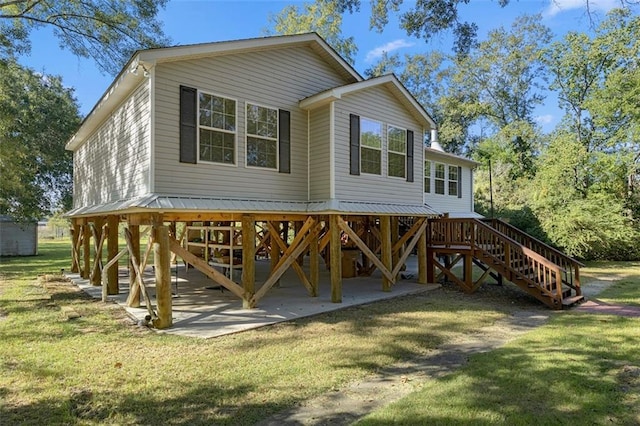 rear view of house with stairs, a yard, and a patio