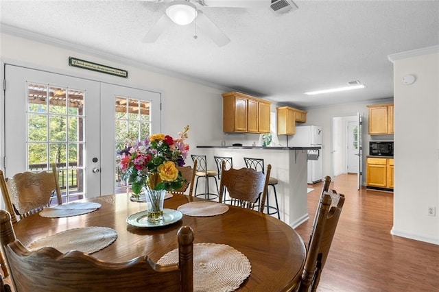 dining room with ornamental molding, ceiling fan, hardwood / wood-style flooring, and french doors