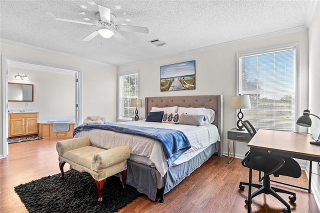 bedroom with visible vents, a textured ceiling, crown molding, and wood finished floors