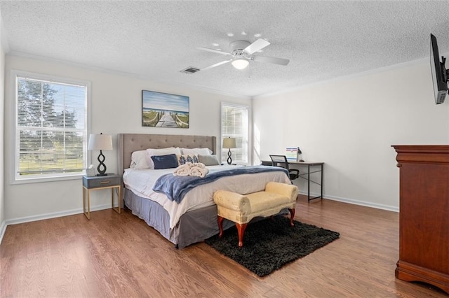 bedroom with a textured ceiling, ornamental molding, hardwood / wood-style floors, and ceiling fan