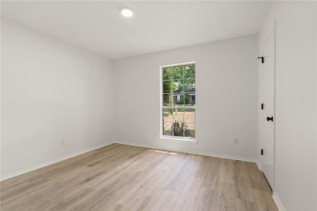unfurnished room with baseboards and light wood-style floors