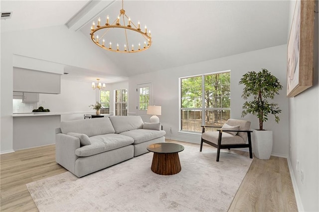 living room with an inviting chandelier, baseboards, light wood-type flooring, and beam ceiling