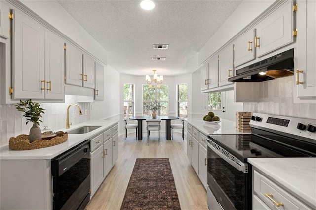 kitchen with a textured ceiling, under cabinet range hood, stainless steel electric range oven, black dishwasher, and a sink