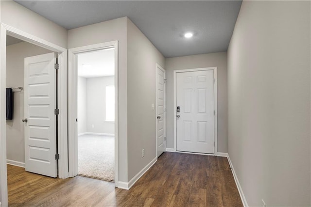 hallway with dark wood finished floors and baseboards