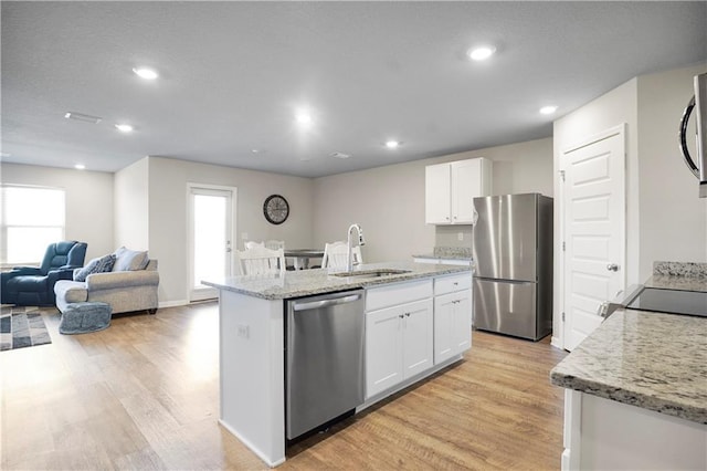 kitchen with stainless steel appliances, light wood-style floors, white cabinetry, a sink, and an island with sink