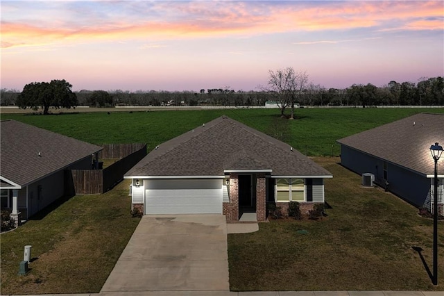 view of front of home featuring concrete driveway, roof with shingles, an attached garage, fence, and brick siding