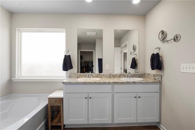 bathroom featuring a garden tub, a sink, and double vanity