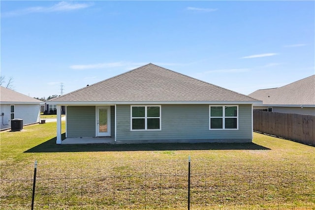 rear view of house with a yard, roof with shingles, fence, and central AC unit