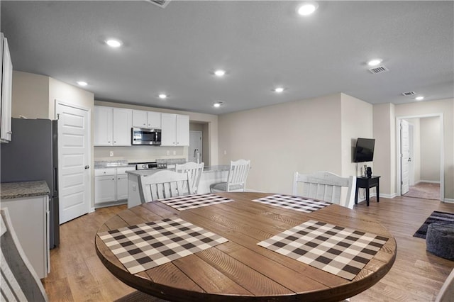 dining space with baseboards, light wood-style flooring, visible vents, and recessed lighting