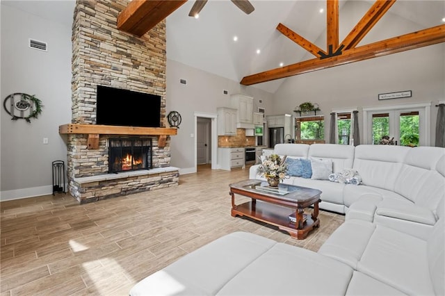 living area with visible vents, beamed ceiling, a stone fireplace, ceiling fan, and high vaulted ceiling