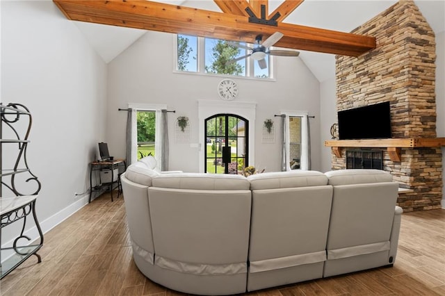 living room featuring wood finished floors, a fireplace, baseboards, high vaulted ceiling, and a ceiling fan