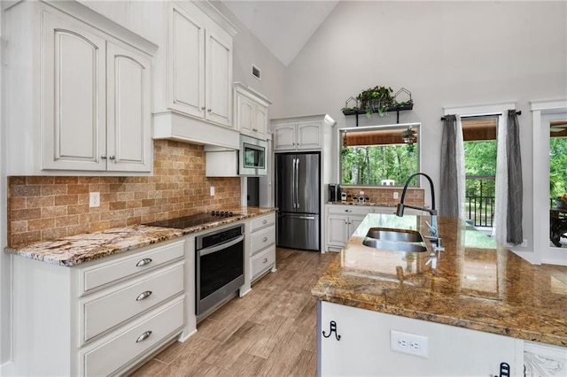 kitchen with a sink, appliances with stainless steel finishes, tasteful backsplash, and stone counters