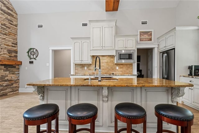 kitchen with stainless steel appliances, visible vents, decorative backsplash, and a sink