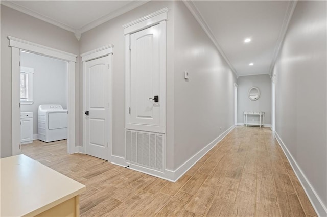hallway featuring washer / clothes dryer, visible vents, baseboards, light wood finished floors, and ornamental molding