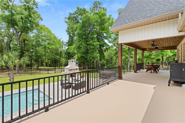 view of patio featuring a fenced in pool, ceiling fan, fence, and a fireplace