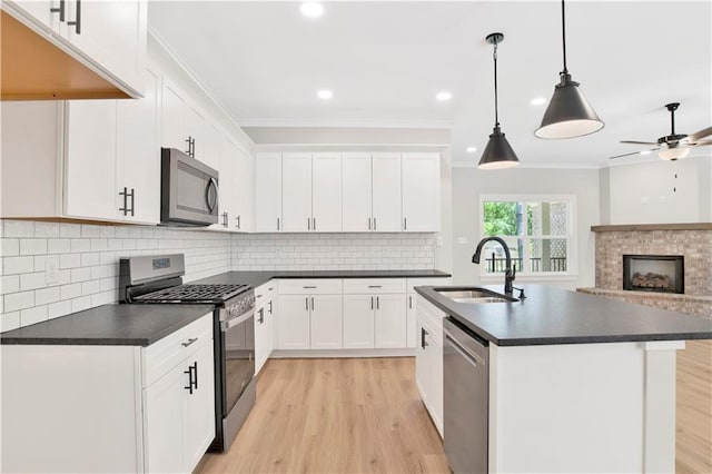 kitchen featuring a sink, dark countertops, light wood-style floors, and stainless steel appliances