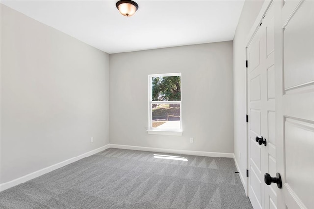carpeted spare room featuring baseboards