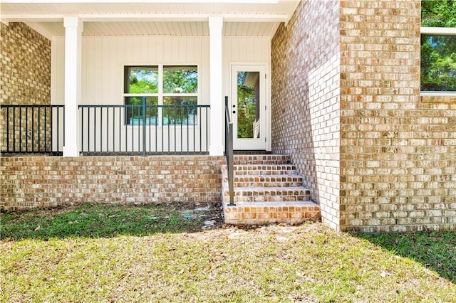 entrance to property featuring brick siding and covered porch