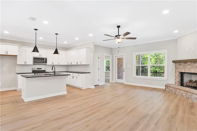 kitchen with open floor plan, appliances with stainless steel finishes, dark countertops, and visible vents